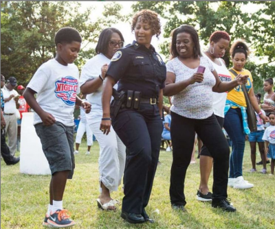 African-American woman police officer dancing with neighbors